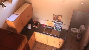 Eine kleine Küche mit Spüle, Schränken und Toilette.