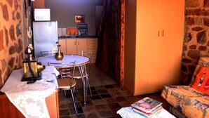 Eine kleine Küche mit Esstisch und Stühlen, inklusive Kühlschrank und Mikrowelle.
