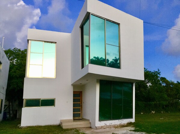 A modern two-story house with large windows and a small front porch.