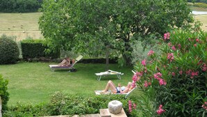 A garden with a stone staircase, a tree, and a grassy area with two people relaxing on sun loungers. - Della Genga (Spoleto)