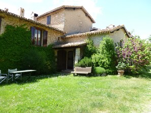 A rustic stone house with a garden, a wooden bench, and a table with chairs. - Della Genga (Spoleto)