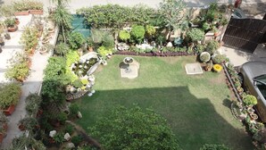 Un jardin bien entretenu, agrémenté de diverses plantes en pot et doté d’une pelouse centrale.