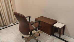 Une pièce comprenant un fauteuil de bureau marron, un bureau en bois et une petite table.