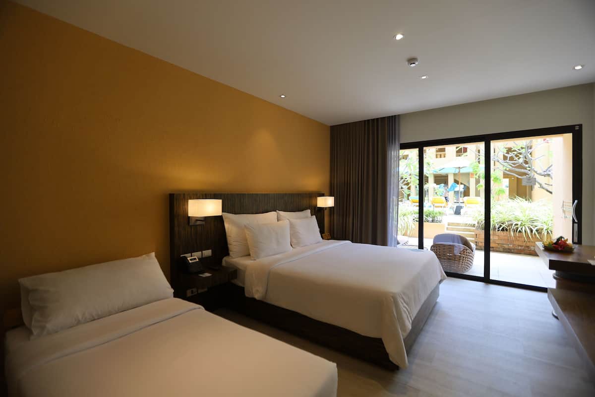 Ein Hotelzimmer mit zwei Betten, einer großen Schiebetür zum Balkon und einer kleinen Sitzecke.