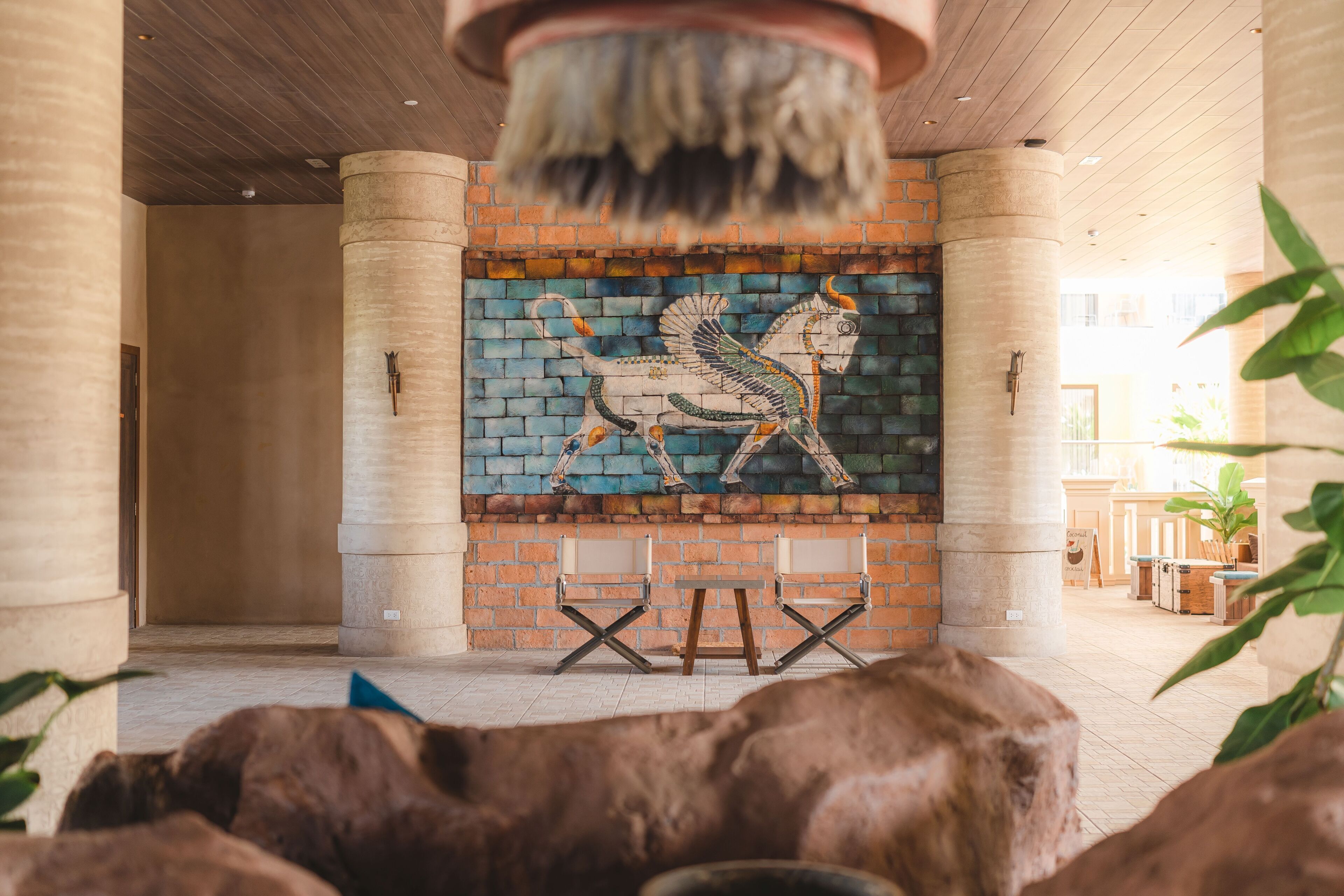 Habitación con un mural de un caballo, pared de ladrillo y techo con vigas de madera. Hay dos sillas plegables frente al mural.