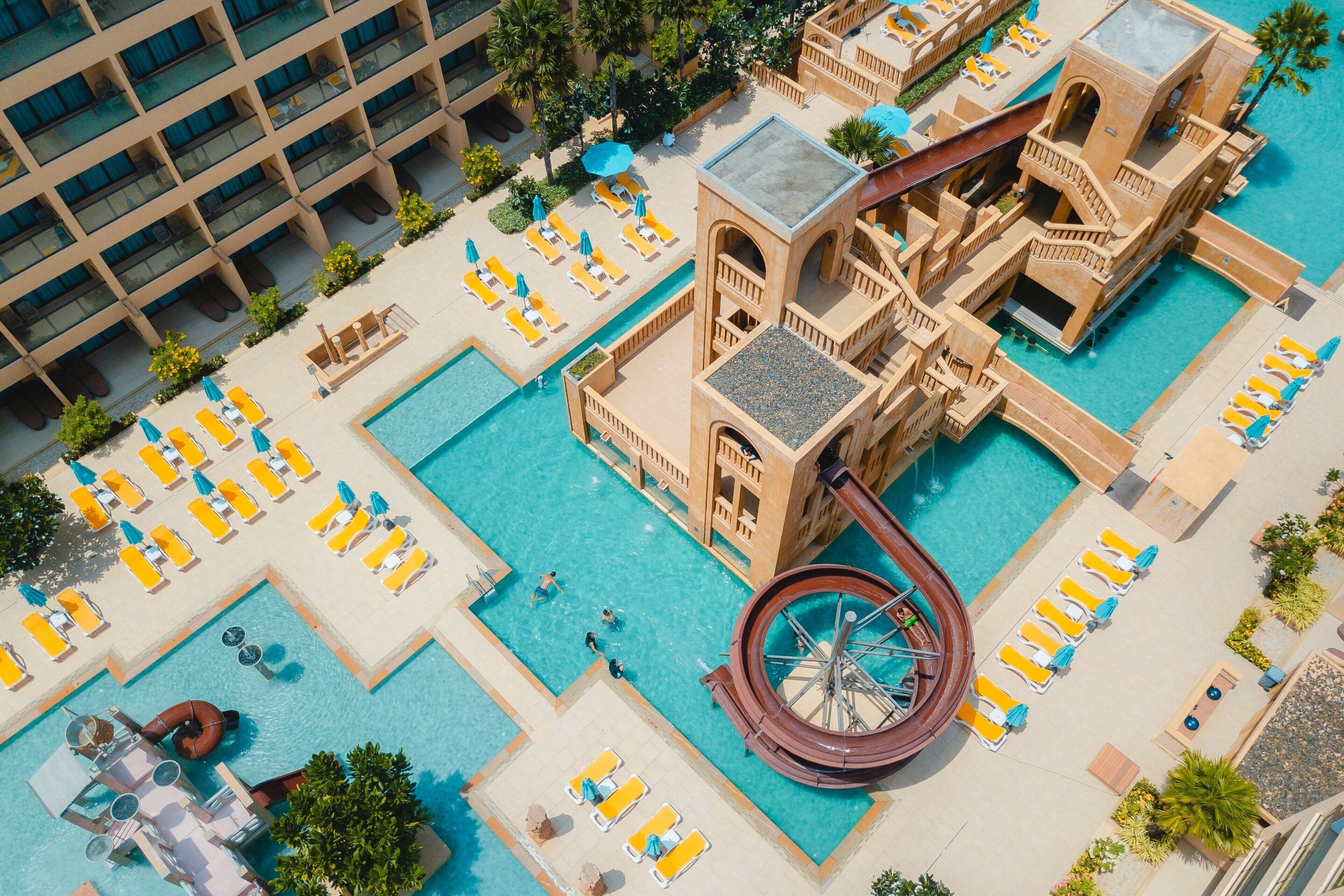 Un área de piscina en la azotea con varios niveles de tumbonas y un tobogán de agua.