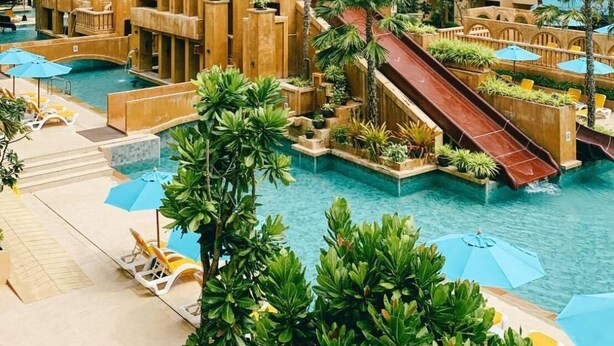 A resort with a central pool, multiple slides, and a multi-story building with balconies.
