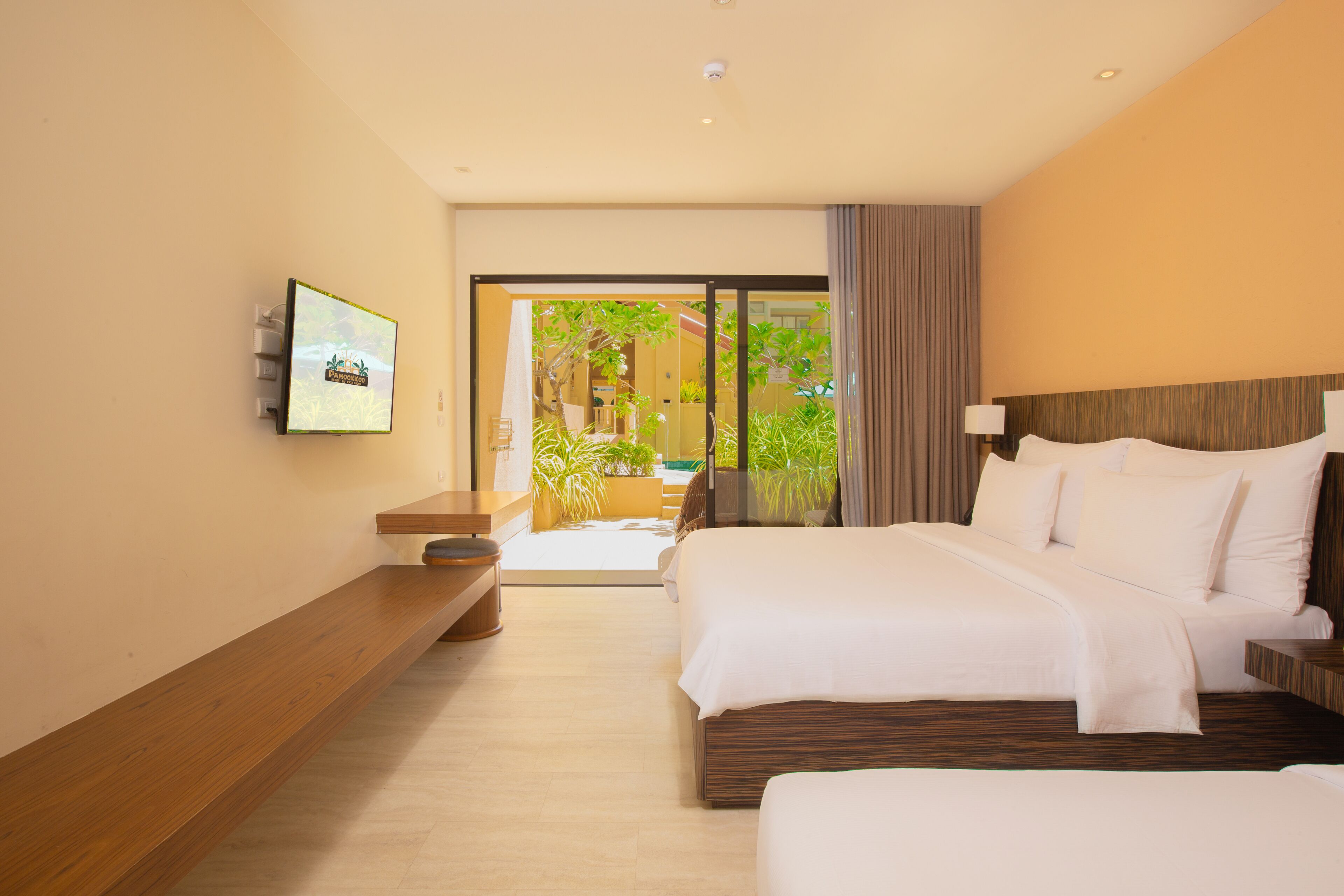 A hotel room with a bed, bedside table, and a television mounted on the wall.
