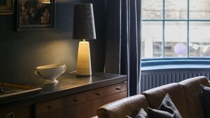 A cozy room with a dark wall, a window with curtains, a lamp, a bowl, and a sofa. - A stunning Grade II listed apartment in the heart of the conservation area. (Deal)