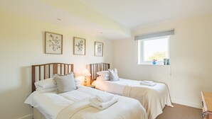 Habitación de hotel con dos camas, ventana con vistas y obras de arte colgadas en la pared.