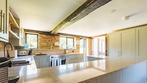 A kitchen with a large island, built-in oven, and a window overlooking greenery.