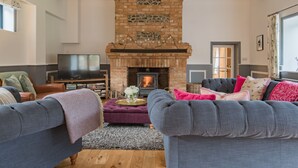 A living room with a fireplace, sofas, a television, and a bookshelf.