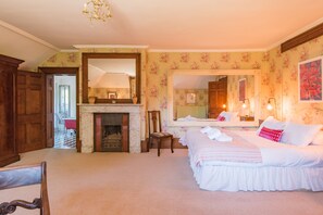 A bedroom with a fireplace, a large mirror, and a bed with white bedding.