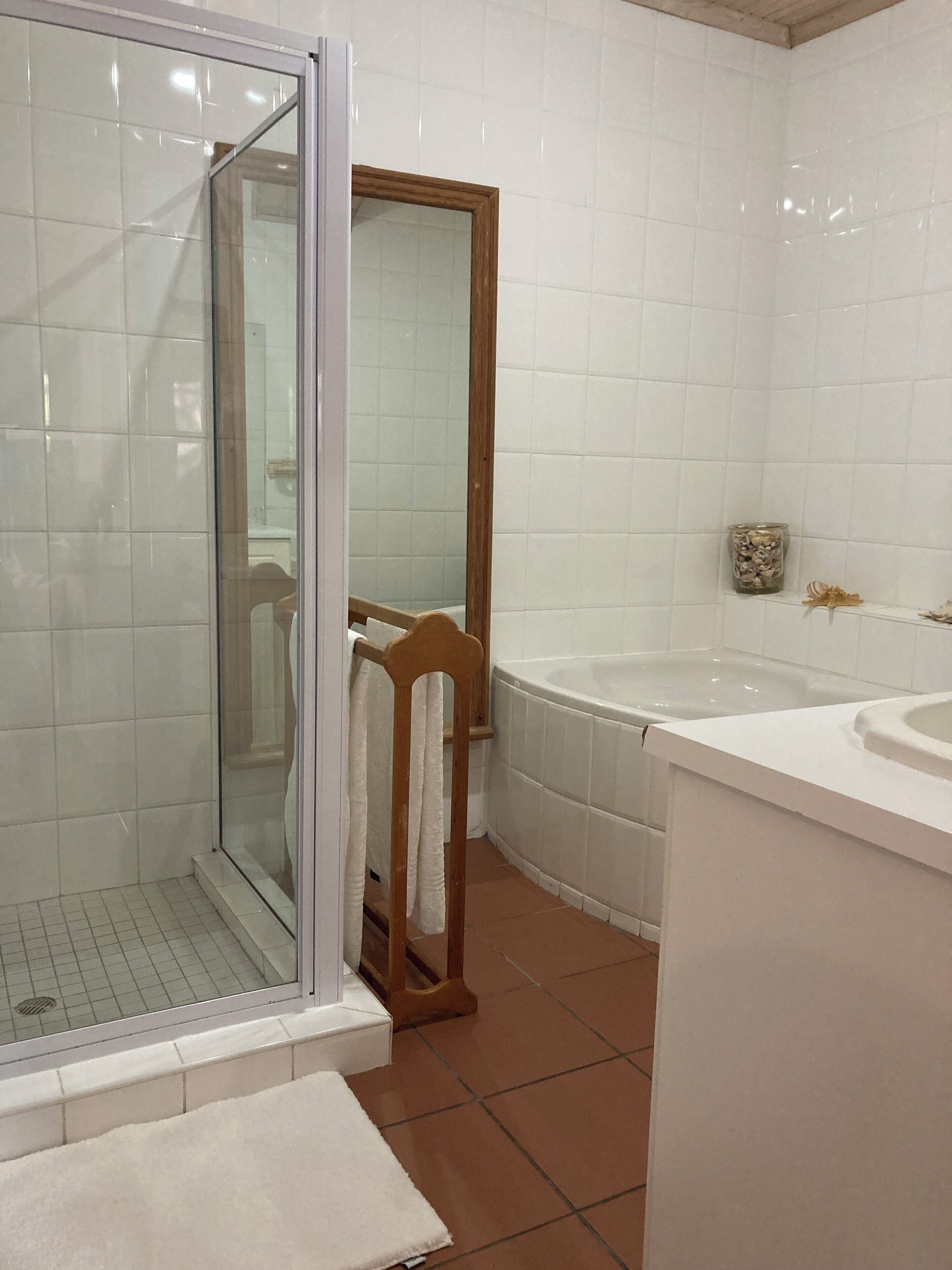 Une salle de bain avec une douche à parois de verre, une chaise en bois, une baignoire et un lavabo.