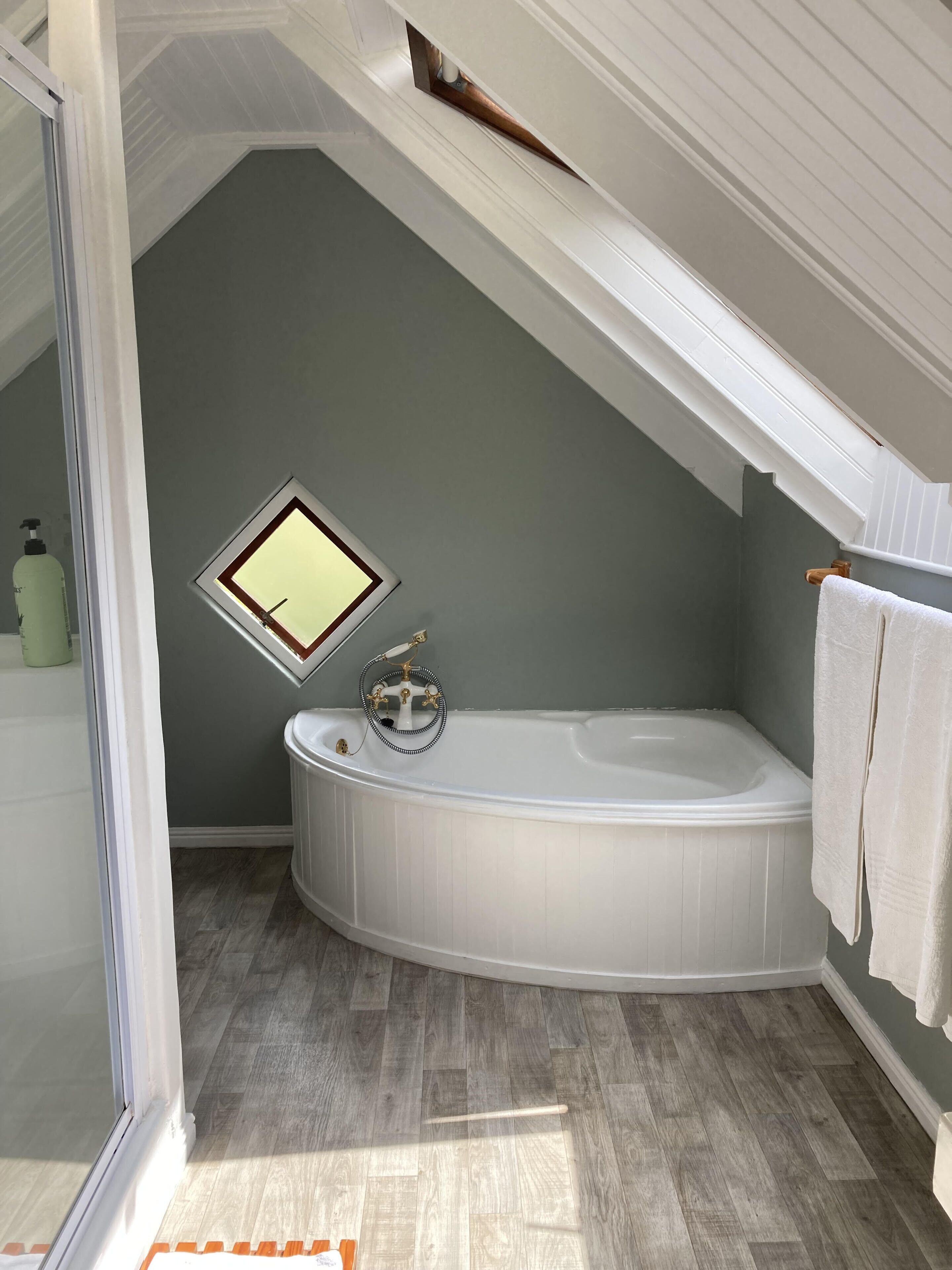A bathroom with a freestanding bathtub, a small window, and a towel rack.