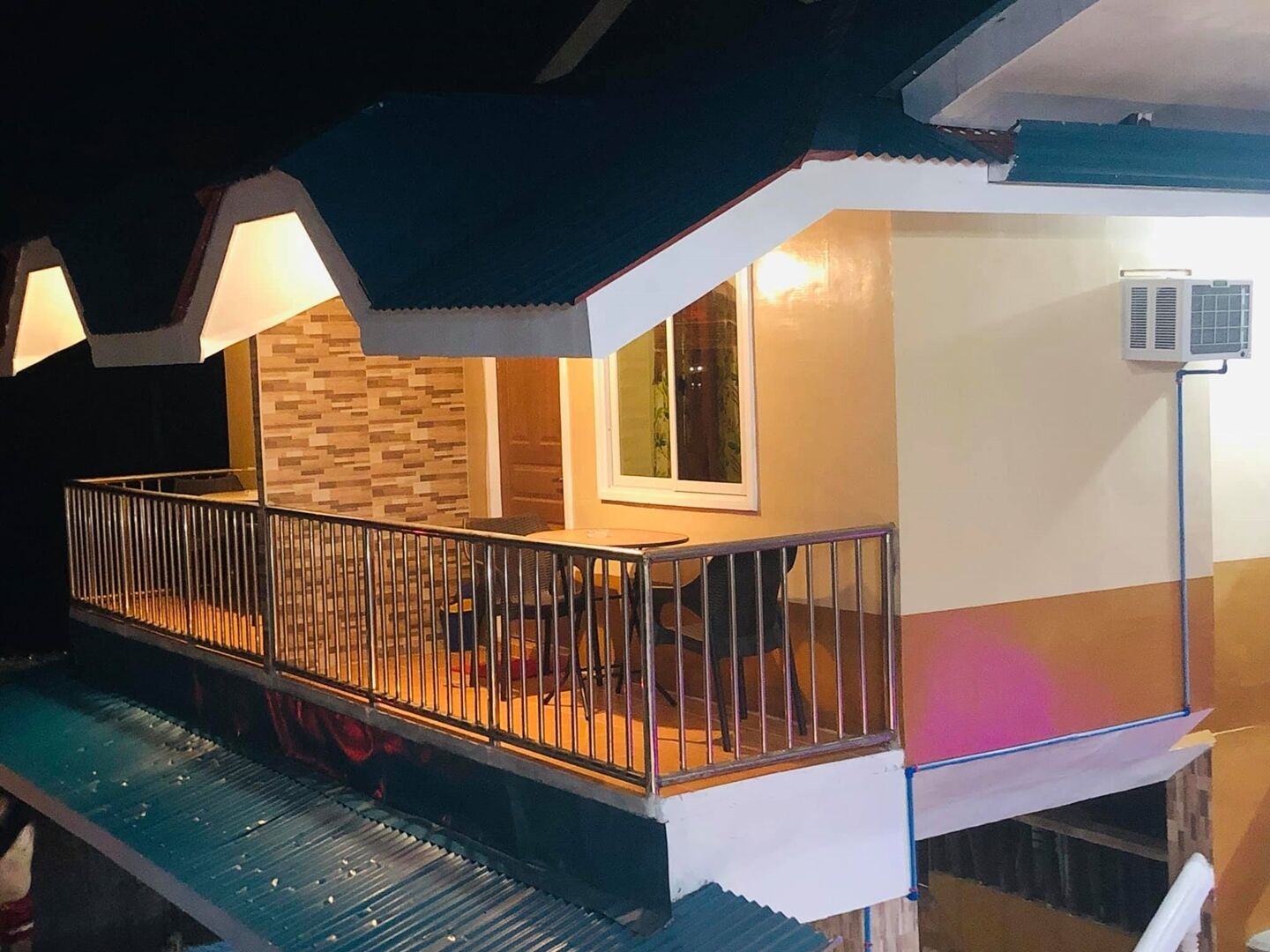 A two-story building with a balcony, a window, and an air conditioning unit.