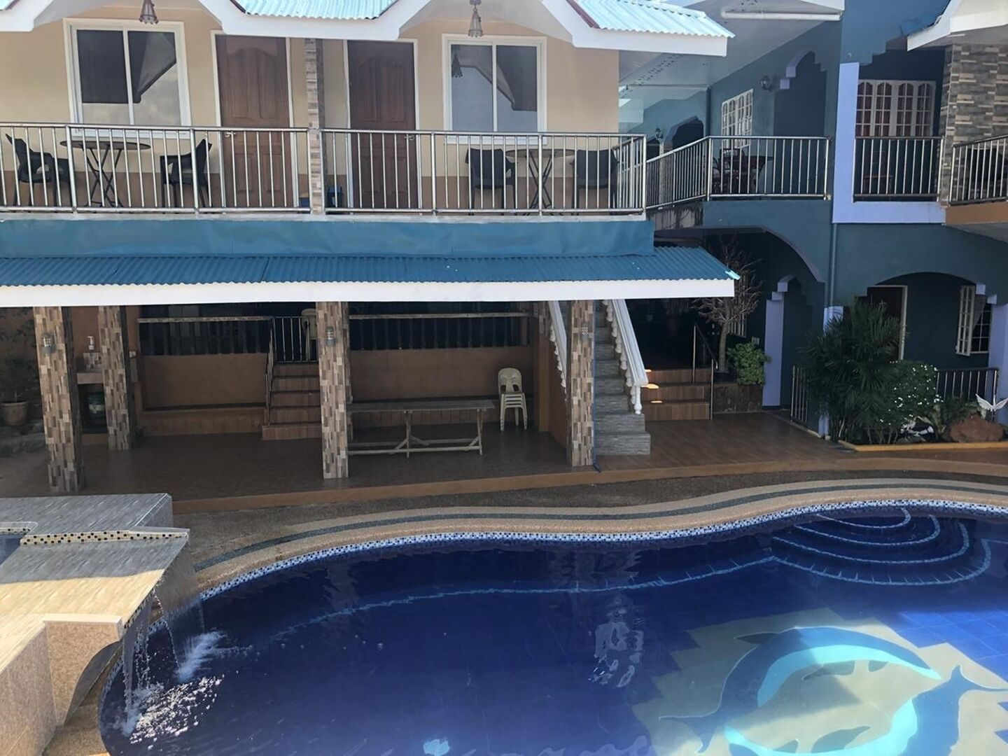 A multi-level house with a swimming pool, outdoor seating, and a covered patio area.