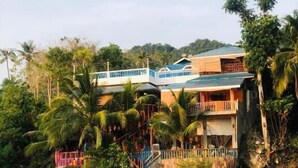 A two-story building with a balcony, surrounded by tropical vegetation and a beach. - Seaview Beach Resort (Anda)