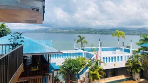 A view of a building with a blue roof and white walls, overlooking a body of water and distant mountains. - Seaview Beach Resort (Anda)