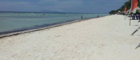 Una playa con arena y algunas banderas rojas.