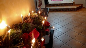 Een warm verlichte gang met een kerstboom, een trap die naar een kamer leidt, en een deur aan het einde.
