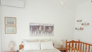 Een slaapkamer met een bed, nachtkastjes, een lamp, een ledikant en wanddecoratie.