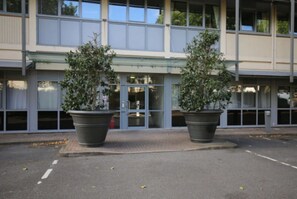 Stylish building with a flat facade and large windows, surrounded by lush greenery.