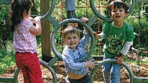 Children playing on a playground structure with interconnected rings.