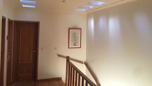 A hallway with a wooden door, a framed picture on the wall, and skylights on the ceiling. - Apartamento Senadomum (Seia)