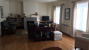 A living room with a fireplace, a television, a bookshelf, and a dining area. - Apartamento Senadomum (Seia)
