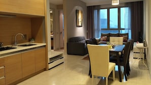 Una cocina moderna con estufa y lavamanos integrados, una zona de comedor con mesa y sillas, y una sala de estar con sofá y un ventanal grande.