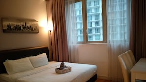 Una habitación de hotel con cama, una silla, una mesa, una lámpara y una ventana con cortinas.