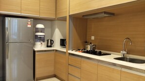 Una cocina compacta equipada con refrigerador, cafetera, hervidor, estufa y pileta.