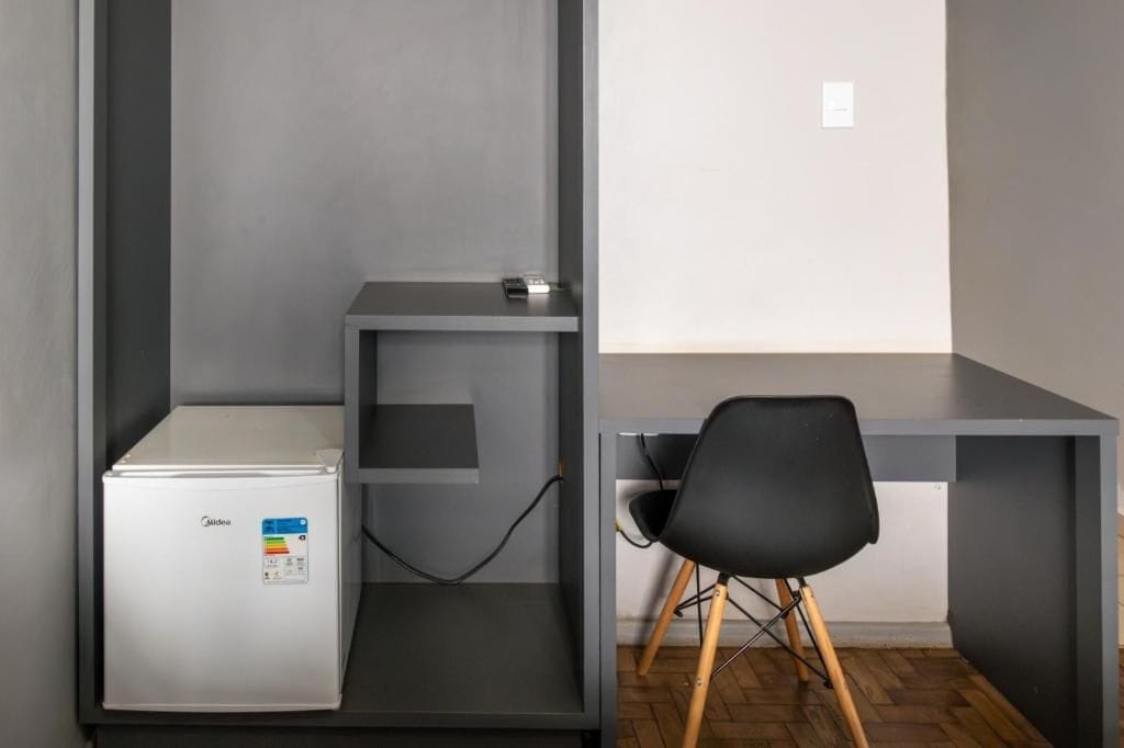 A compact office space with a desk, a chair, and a small refrigerator.