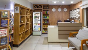 A reception area with a counter, seating, and a refrigerator stocked with beverages. - Euro Hotel (Ubirata)