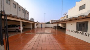 A parking area with multiple cars, a building labeled "ESTACIONAMENTO", and a clear sky. - Euro Hotel (Ubirata)