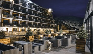 A modern hotel with multiple balconies, outdoor seating areas, and a view of a mountainous landscape. - Gudauri Hills ApartHotel (Kazbegi)
