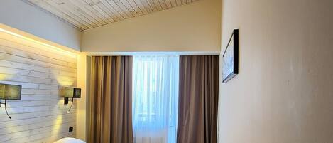 Un dormitorio con techo de madera, una cama, una mesita de noche y un buró.