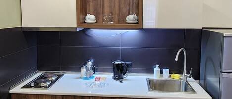 A modern kitchen with wooden cabinets, a white countertop, a sink, and a built-in stove.