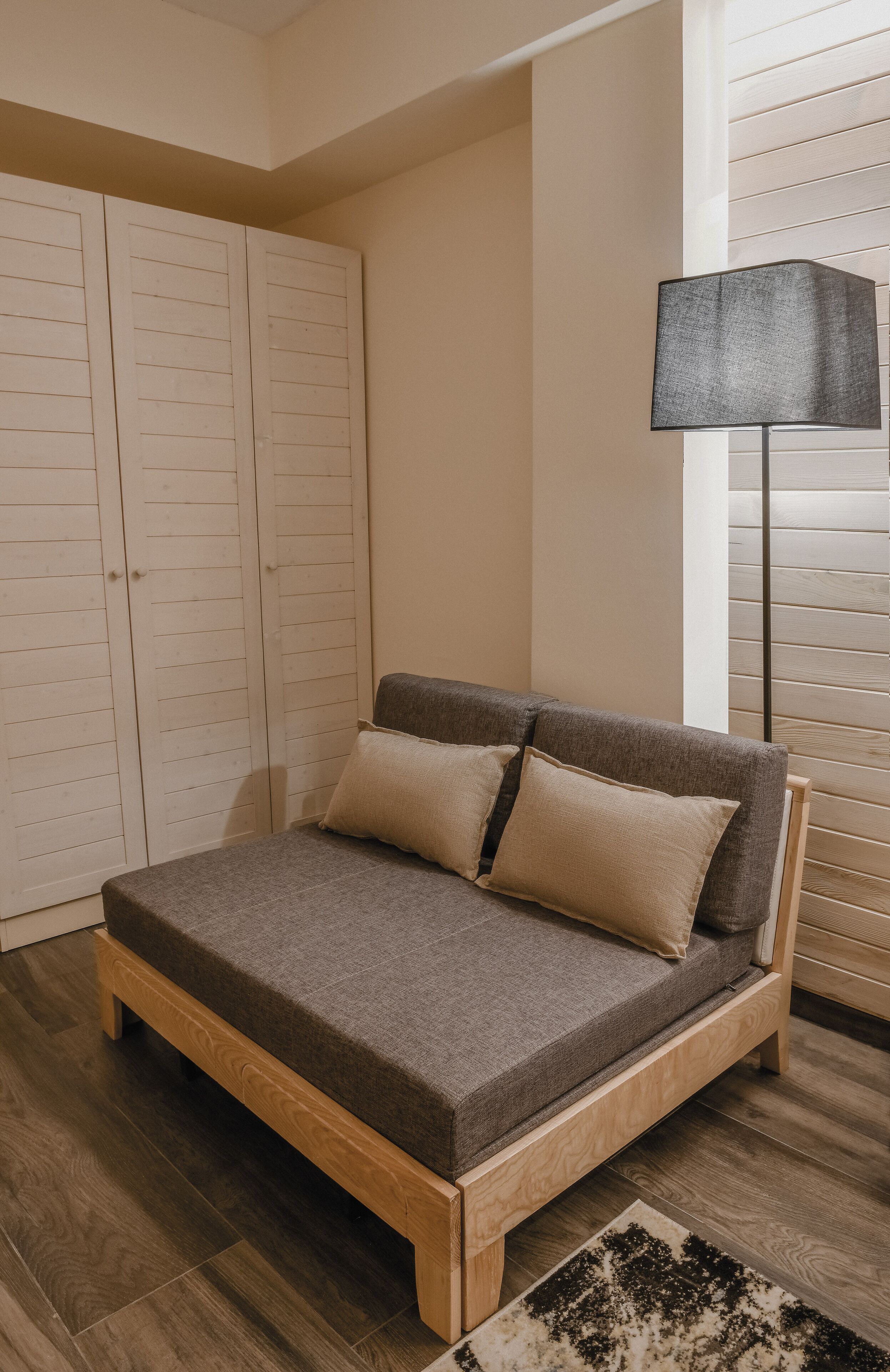 A bedroom with a wooden bed, a wardrobe, and a floor lamp.