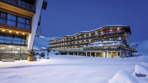 Un hotel de varios pisos con un diseño moderno, con balcones y un paisaje nevado.