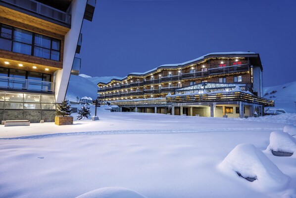 A multi-story hotel with a modern design, featuring balconies and a snow-covered landscape. - Gudauri Hills ApartHotel (Kazbegi)