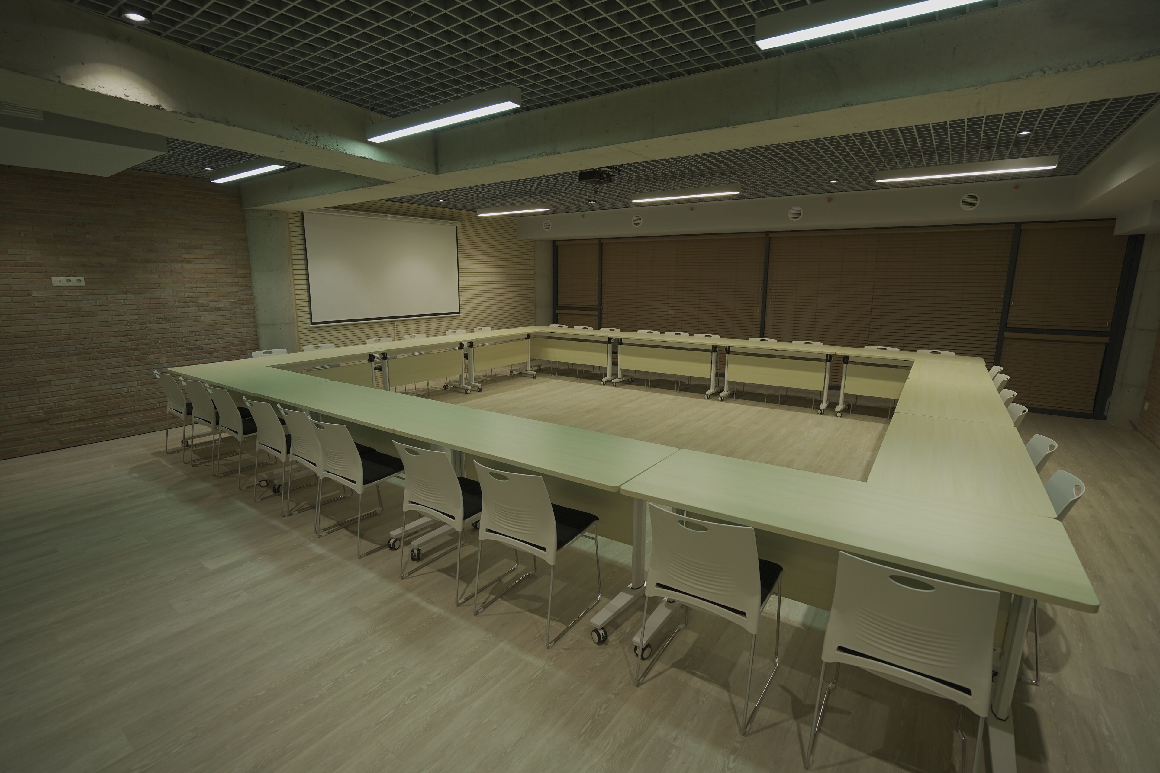 A conference room with a long table, chairs, a projector screen, and a whiteboard.
