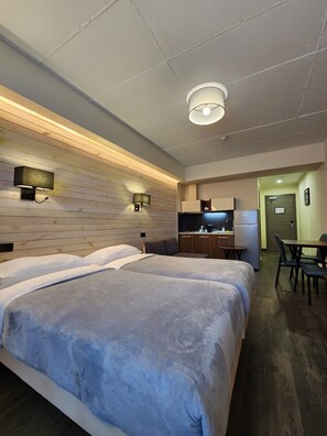 A hotel room with a large bed, a kitchenette, a dining area, and a bathroom. - Gudauri Hills ApartHotel (Kazbegi)
