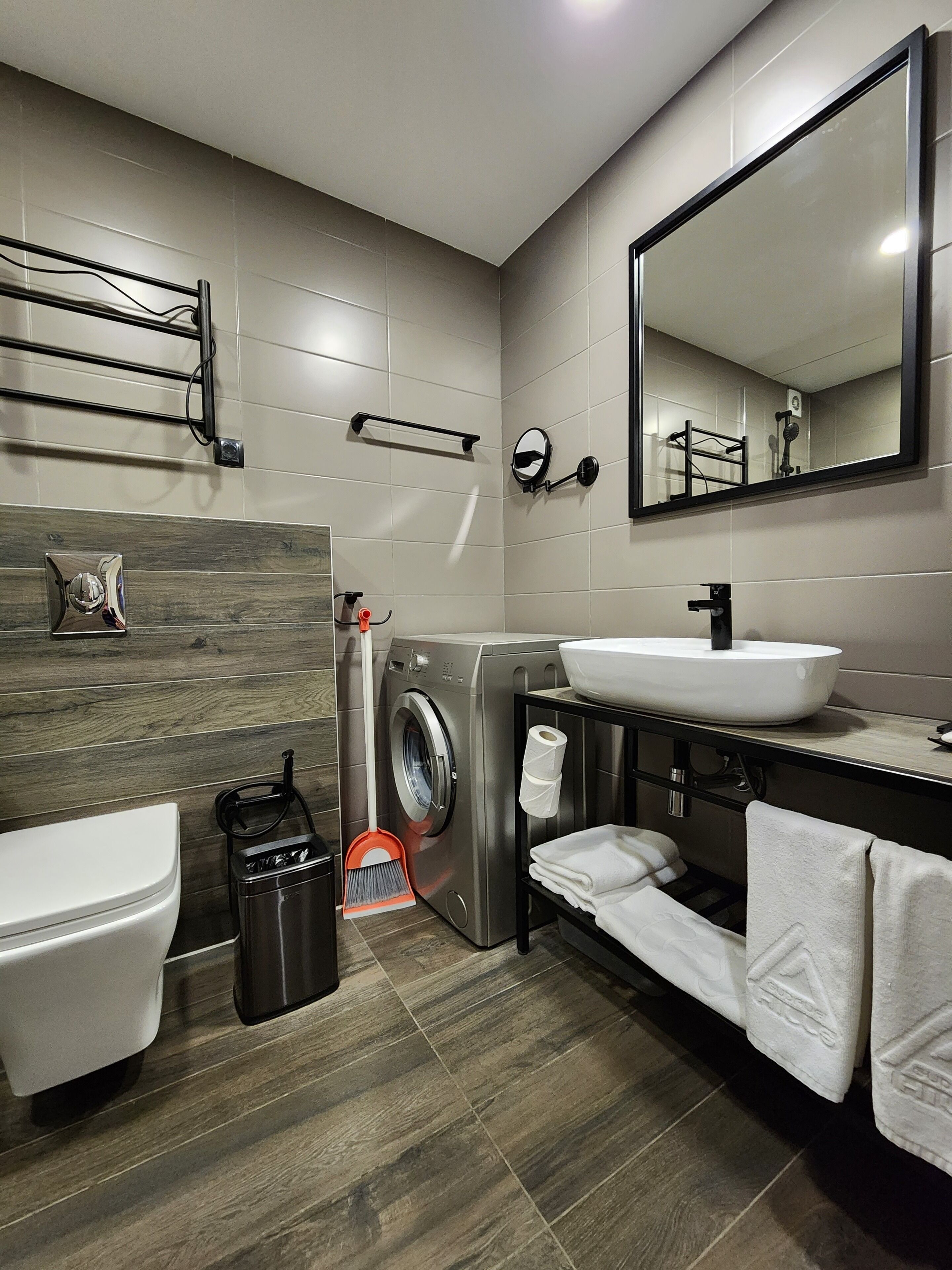 Een moderne badkamer met een wasmachine, een wastafel en een toilet.