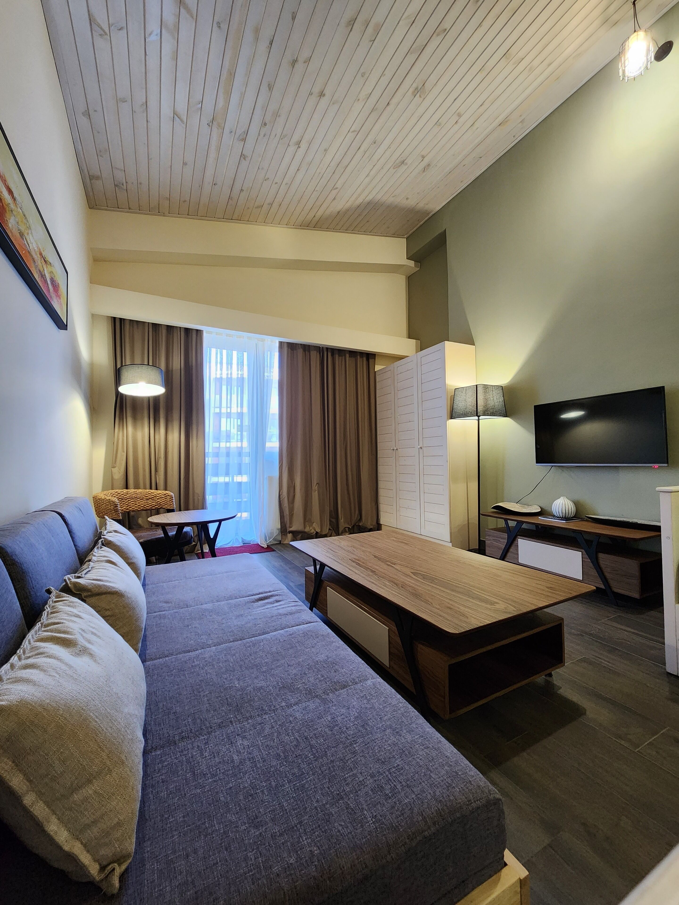 A modern living room with a sofa, a dining table, a TV, and a lamp.