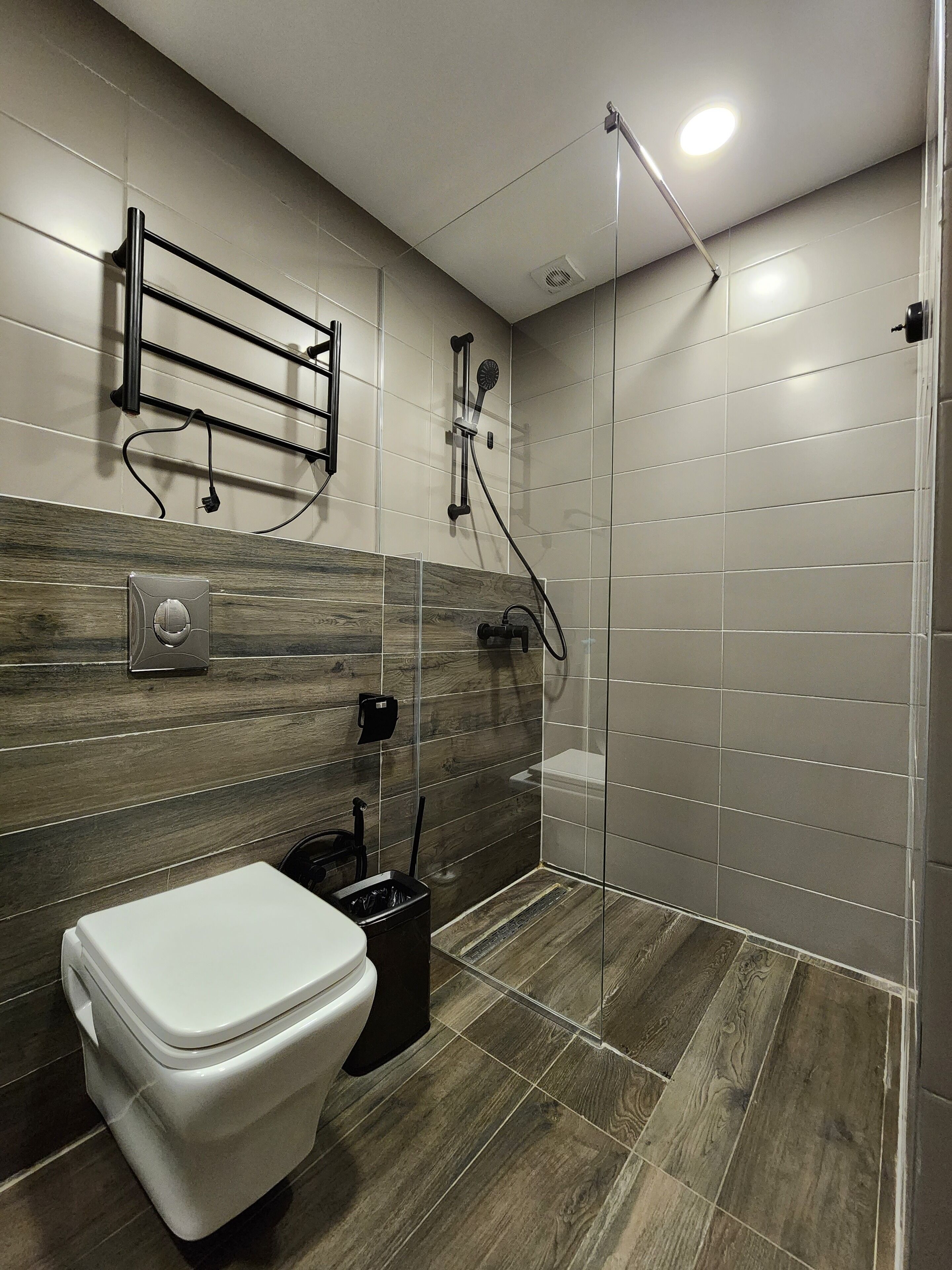 Un baño moderno con ducha, inodoro y toallero.