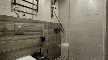 Un baño moderno con ducha, inodoro y toallero.