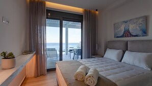 A modern hotel room with a large bed, a balcony with a view of the sea, and a painting on the wall. - Villa Faros (Rhodes)