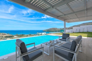 A terrace with a view of a swimming pool and the sea.